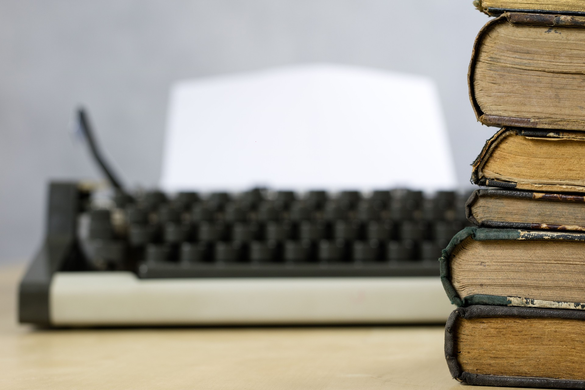 Livros antigos e máquina de escrever sobre uma mesa de madeira. Exibição de livros e uma máquina de escrever sobre uma velha mesa de madeira. Fundo branco