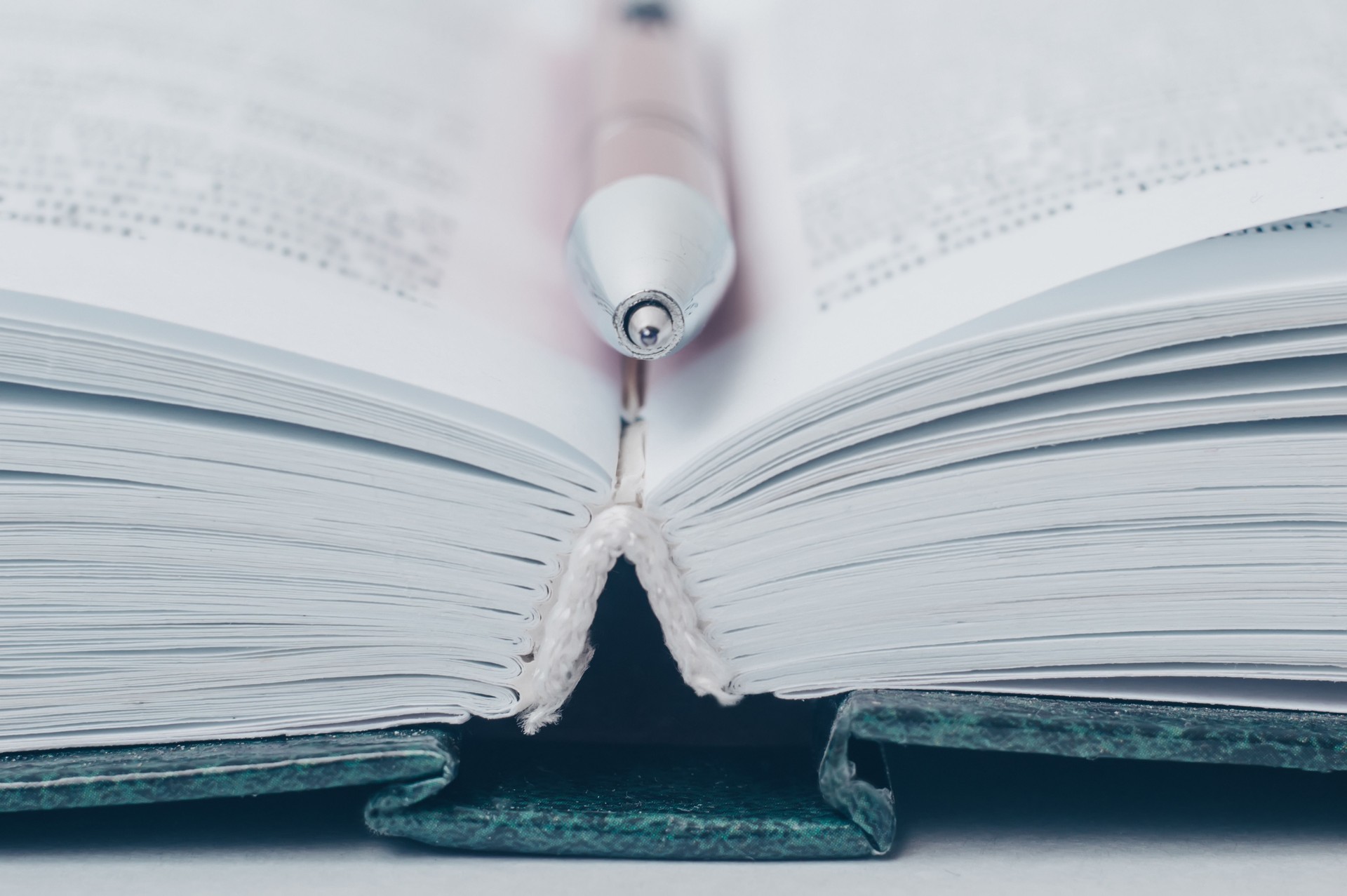 Abra o livro. Uma pena encontra-se entre as páginas em um livro aberto.
